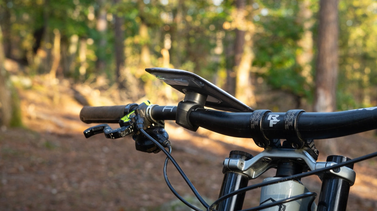 Support téléphone Shapeheart fixé au guidon d'un VTT en forêt